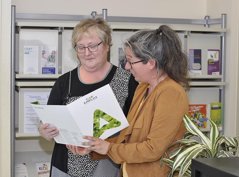 Deux femmes consultant une plaquette dans un bureau